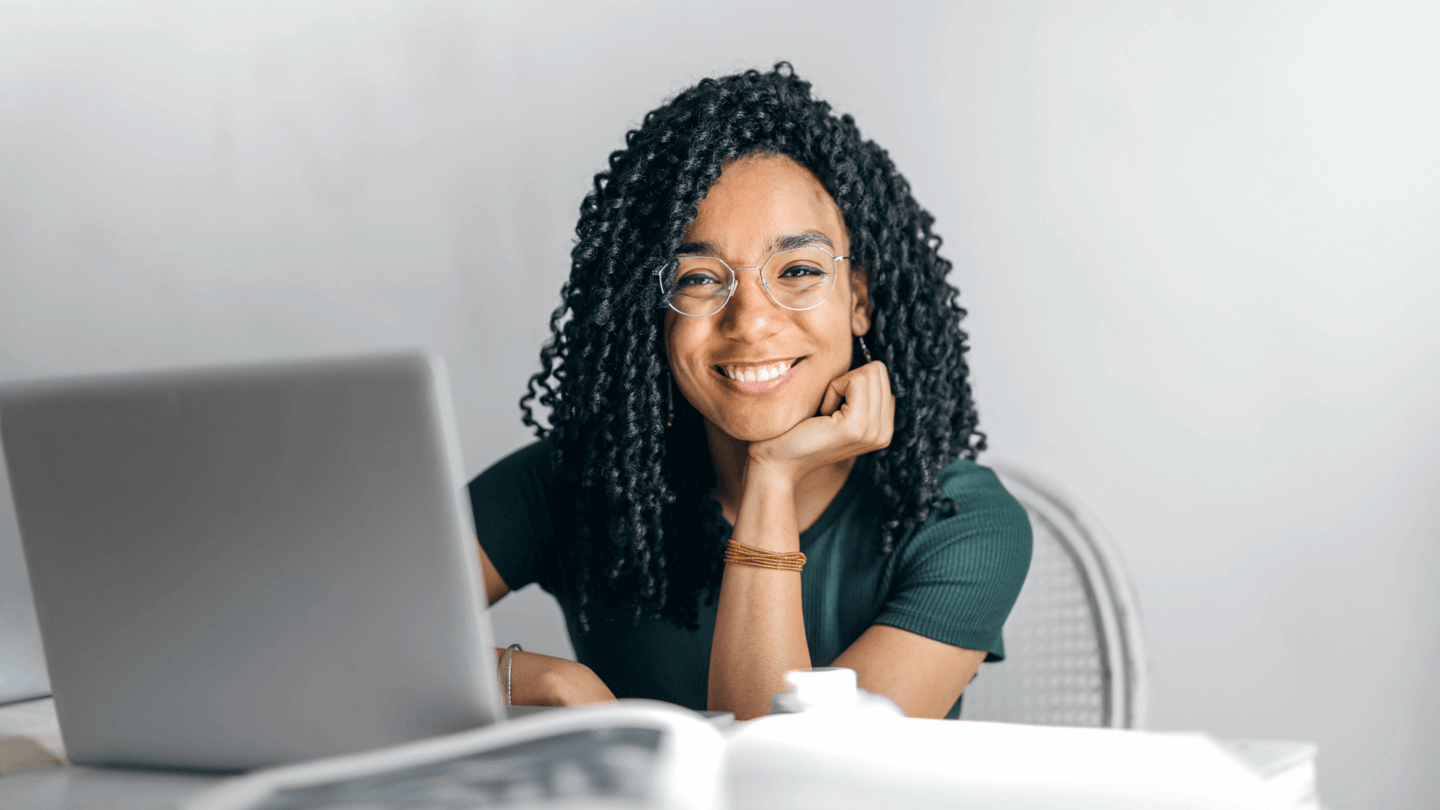 Woman smiling at camera next to laptop