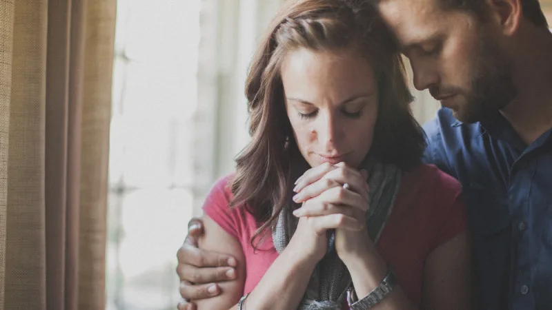 Husband and wife humbly praying with each other