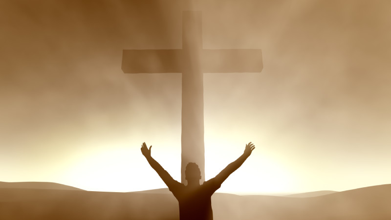 Man with his hands raised in front of the cross