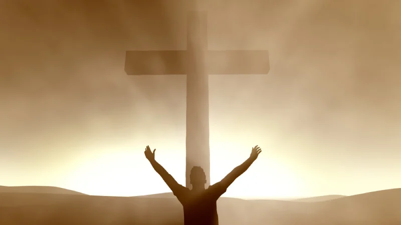 Man with his hands raised in front of the cross