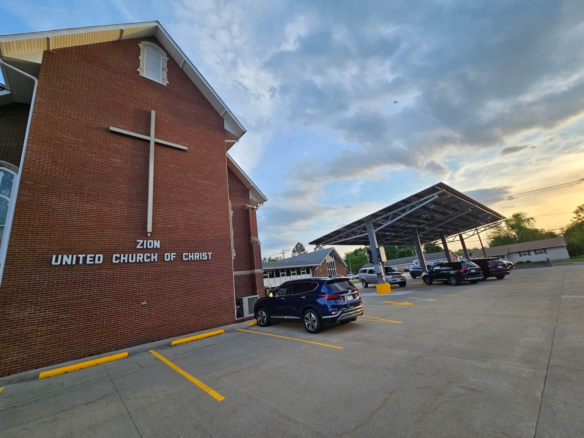 Red brick church building with solar panels in parking lot