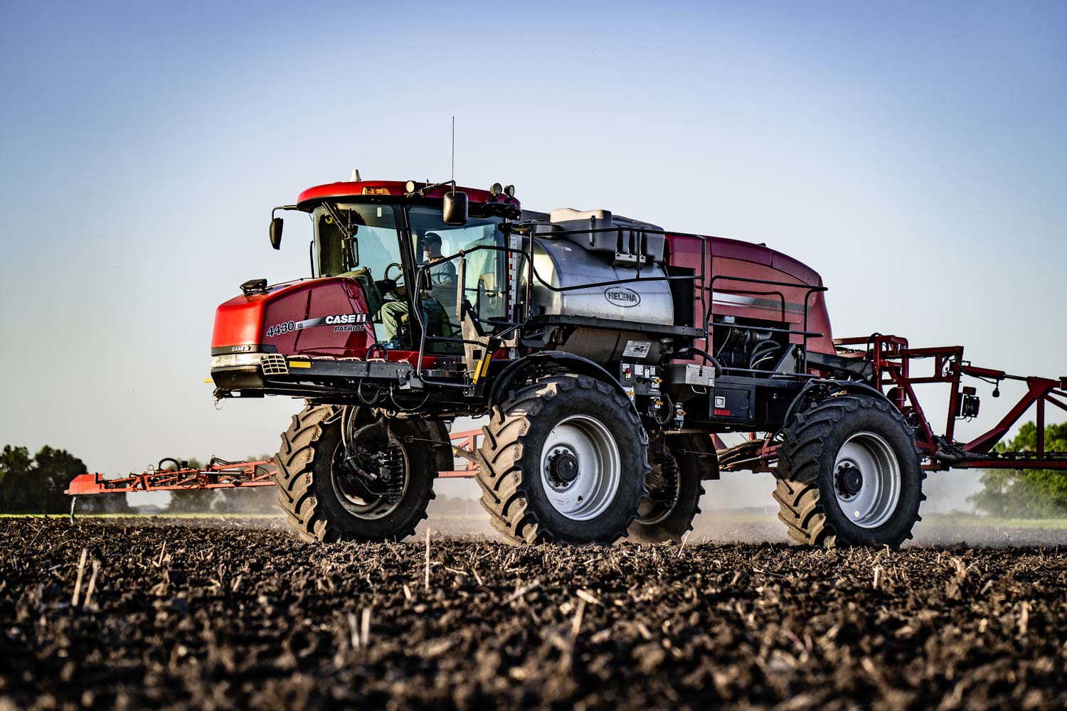 A Case IH 4430 sprayer with 650/65R38 floaters applying a pre-emerge herbicide.