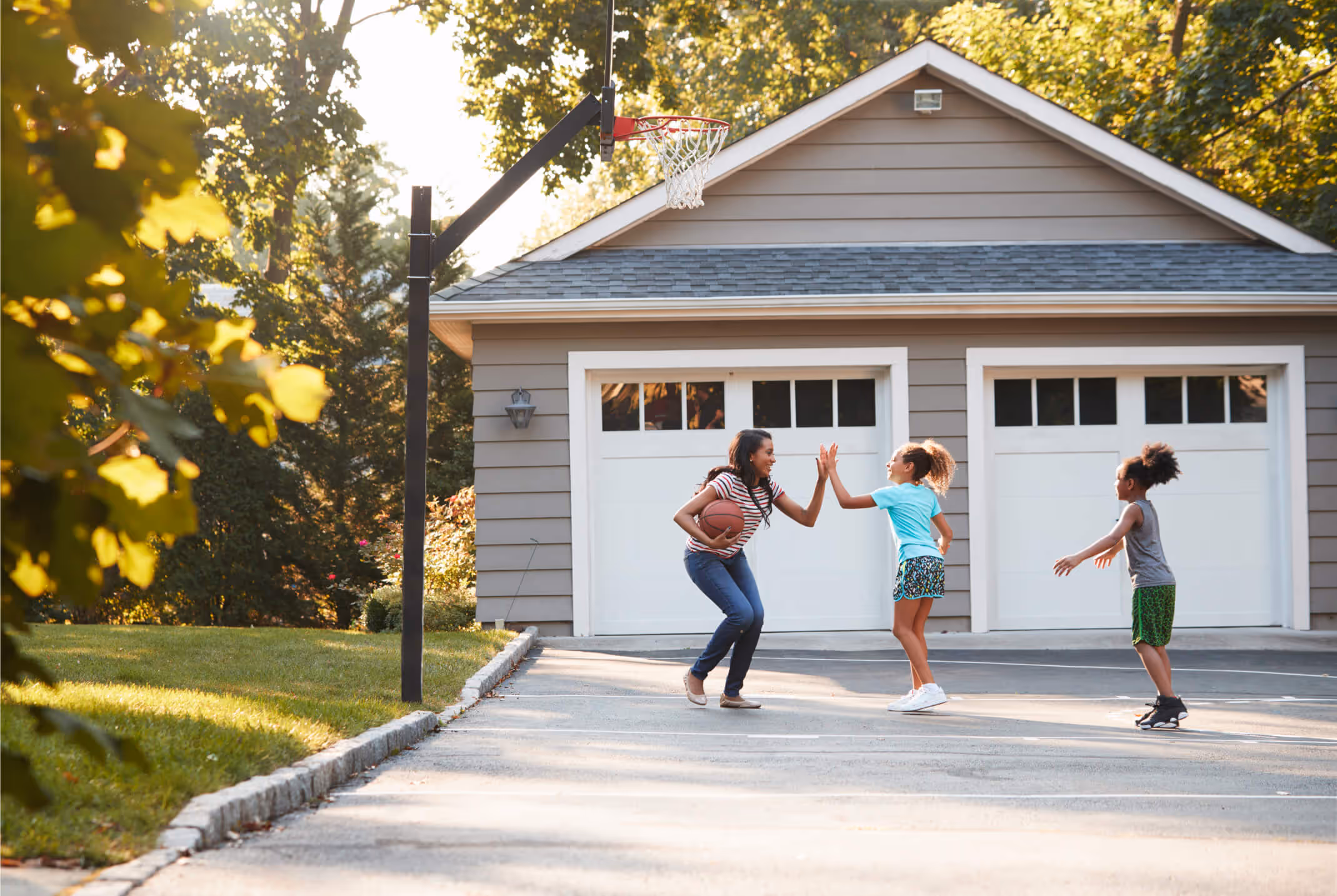 Family enjoying a game of basketball on their driveway.