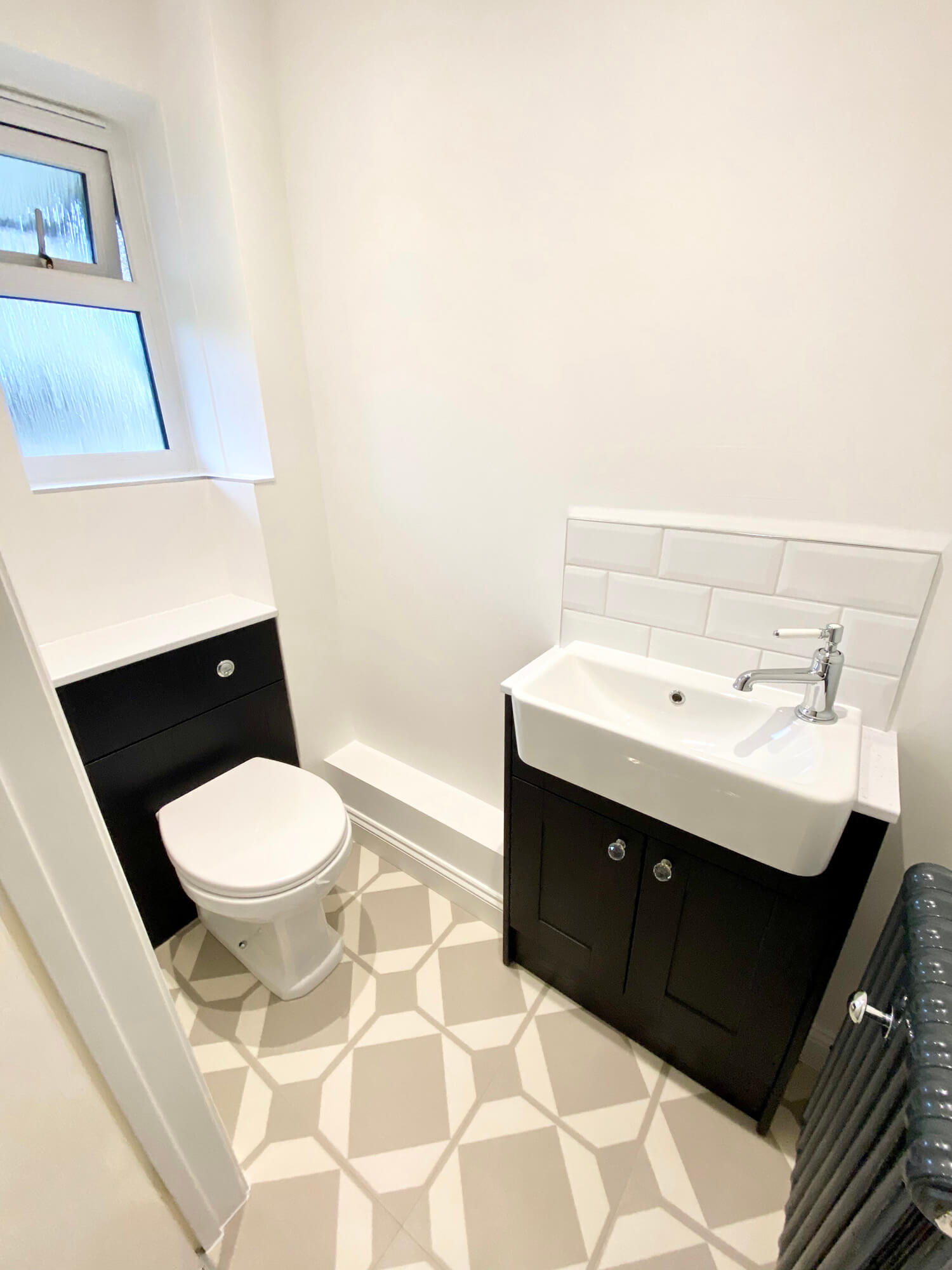 Small toilet room with black bathroom suite and decorative floor tiles.  