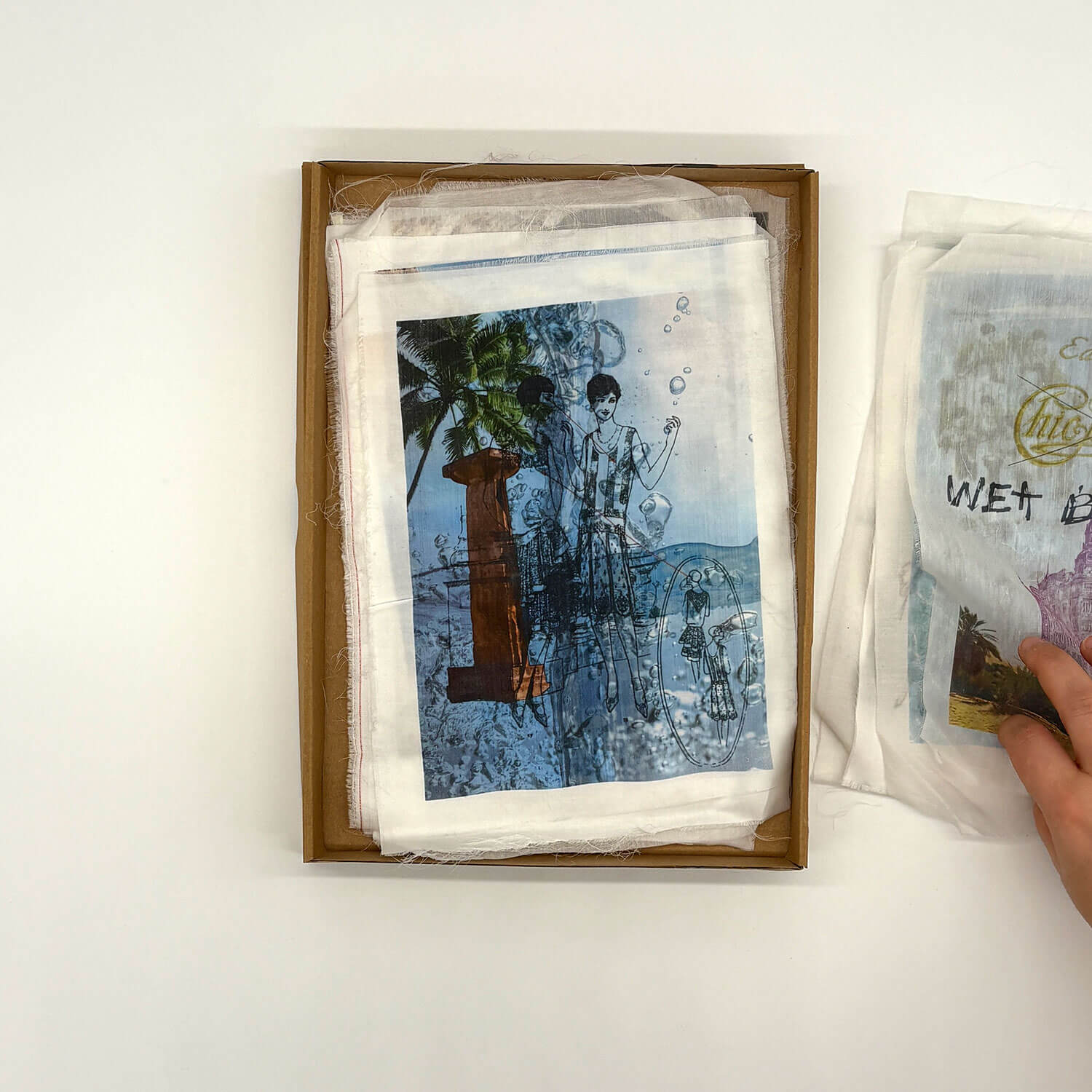 A studio photo of a designer bag and a publication printed on textile