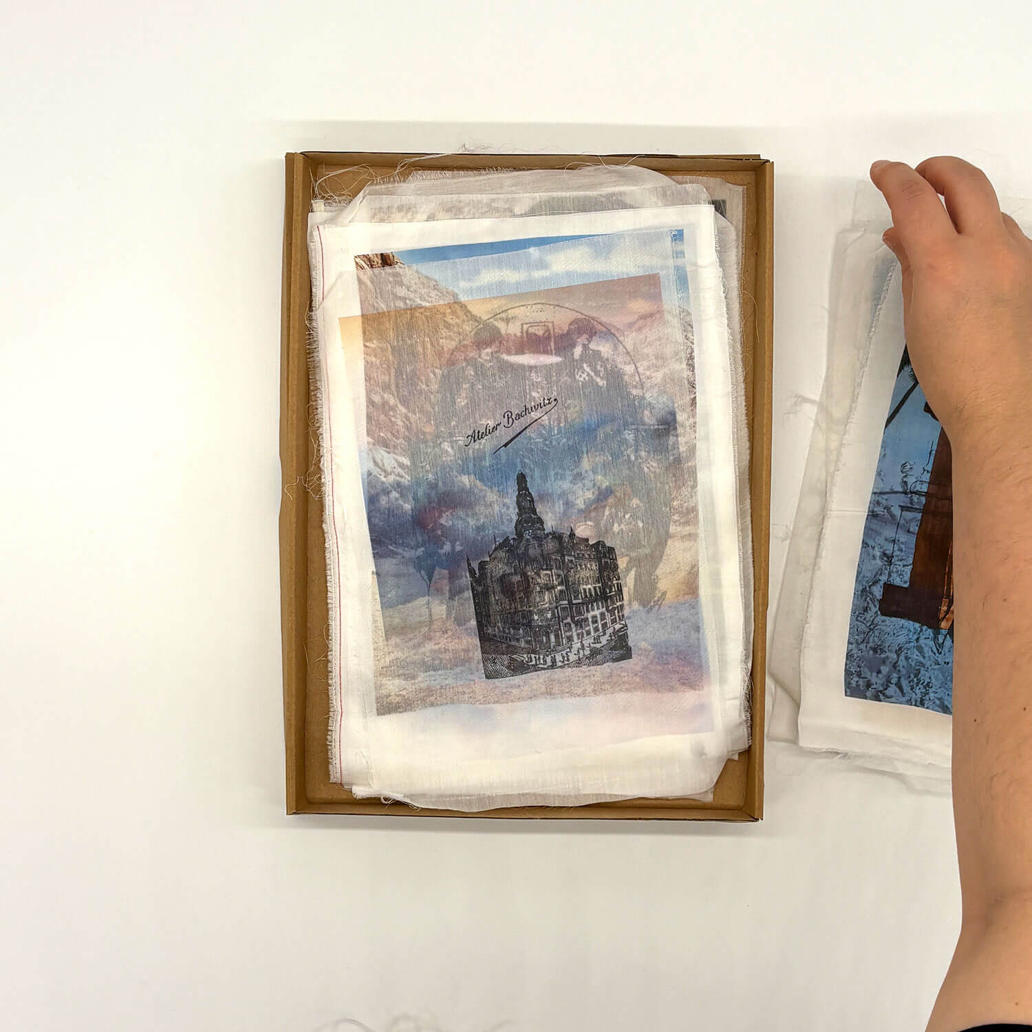 A studio photo of a designer bag and a publication printed on textile