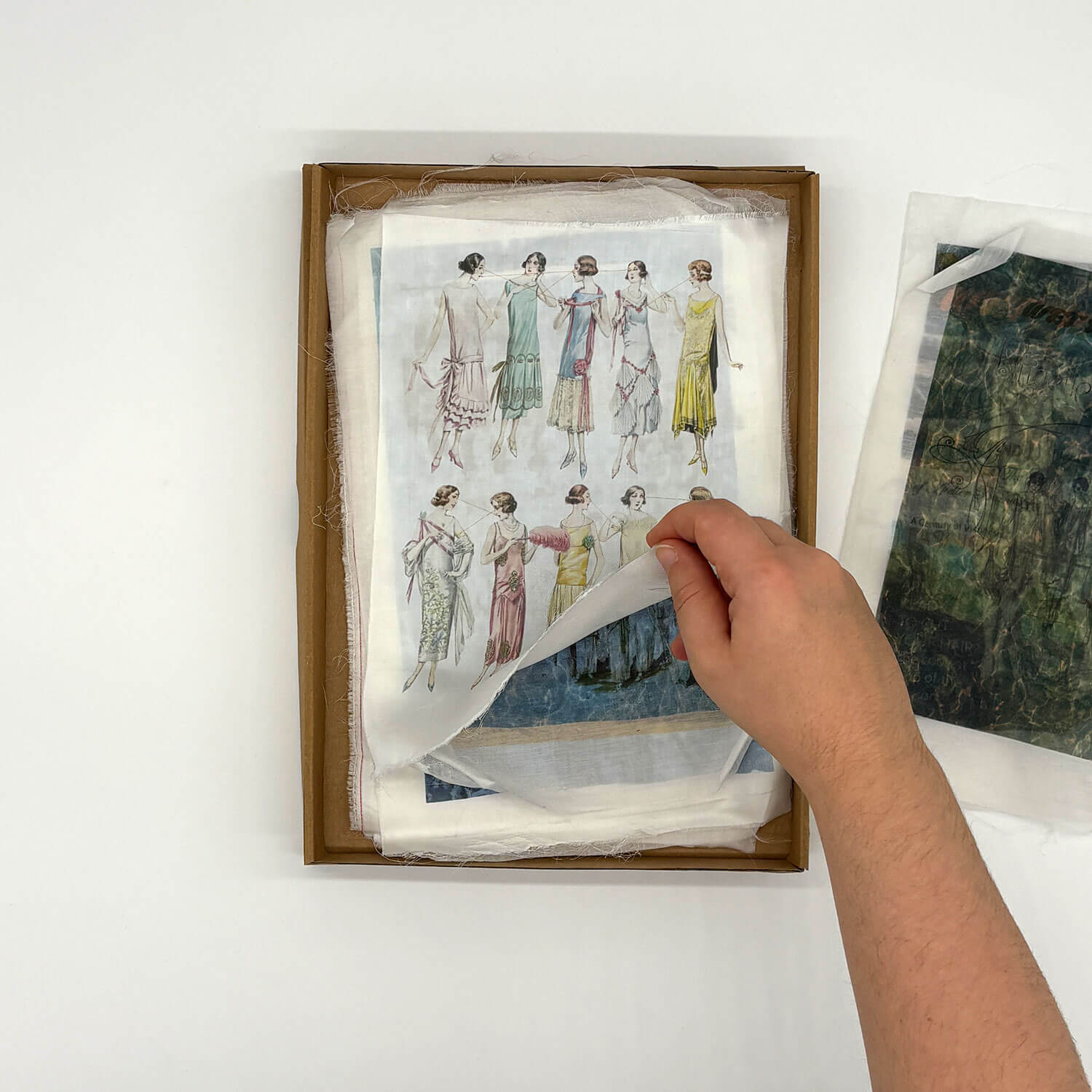 A studio photo of a designer bag and a publication printed on textile