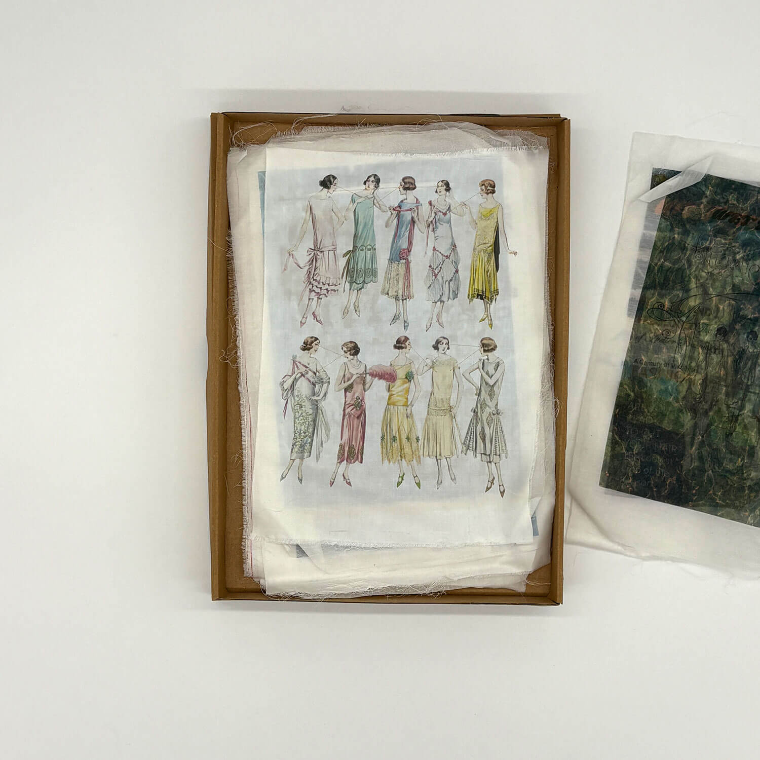 A studio photo of a designer bag and a publication printed on textile