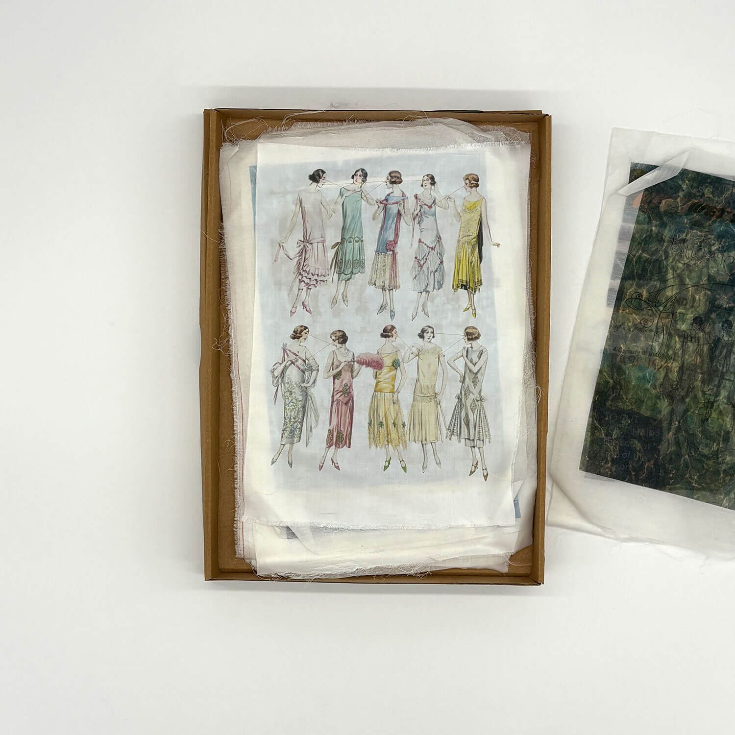 A studio photo of a designer bag and a publication printed on textile