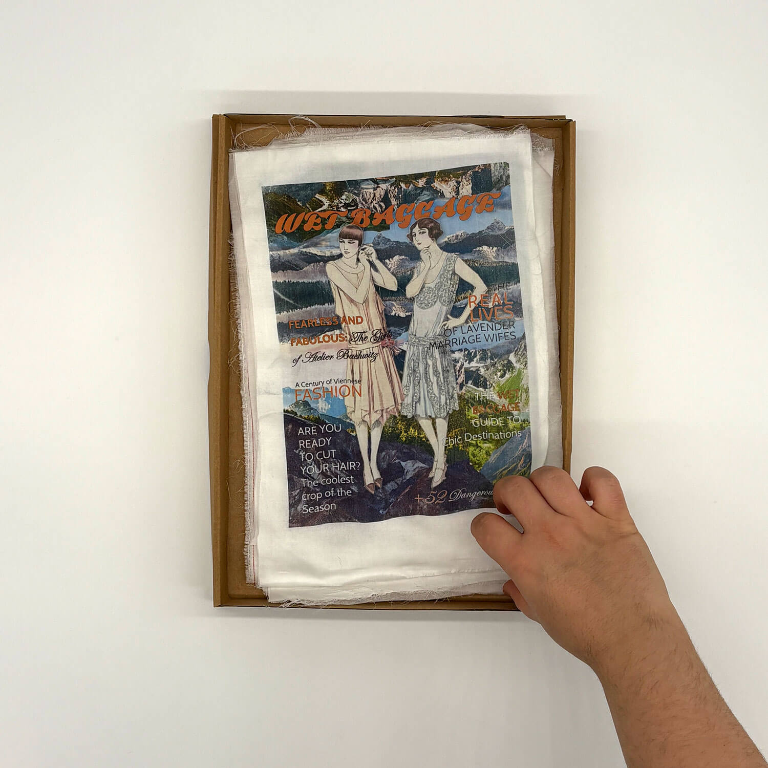 A studio photo of a designer bag and a publication printed on textile