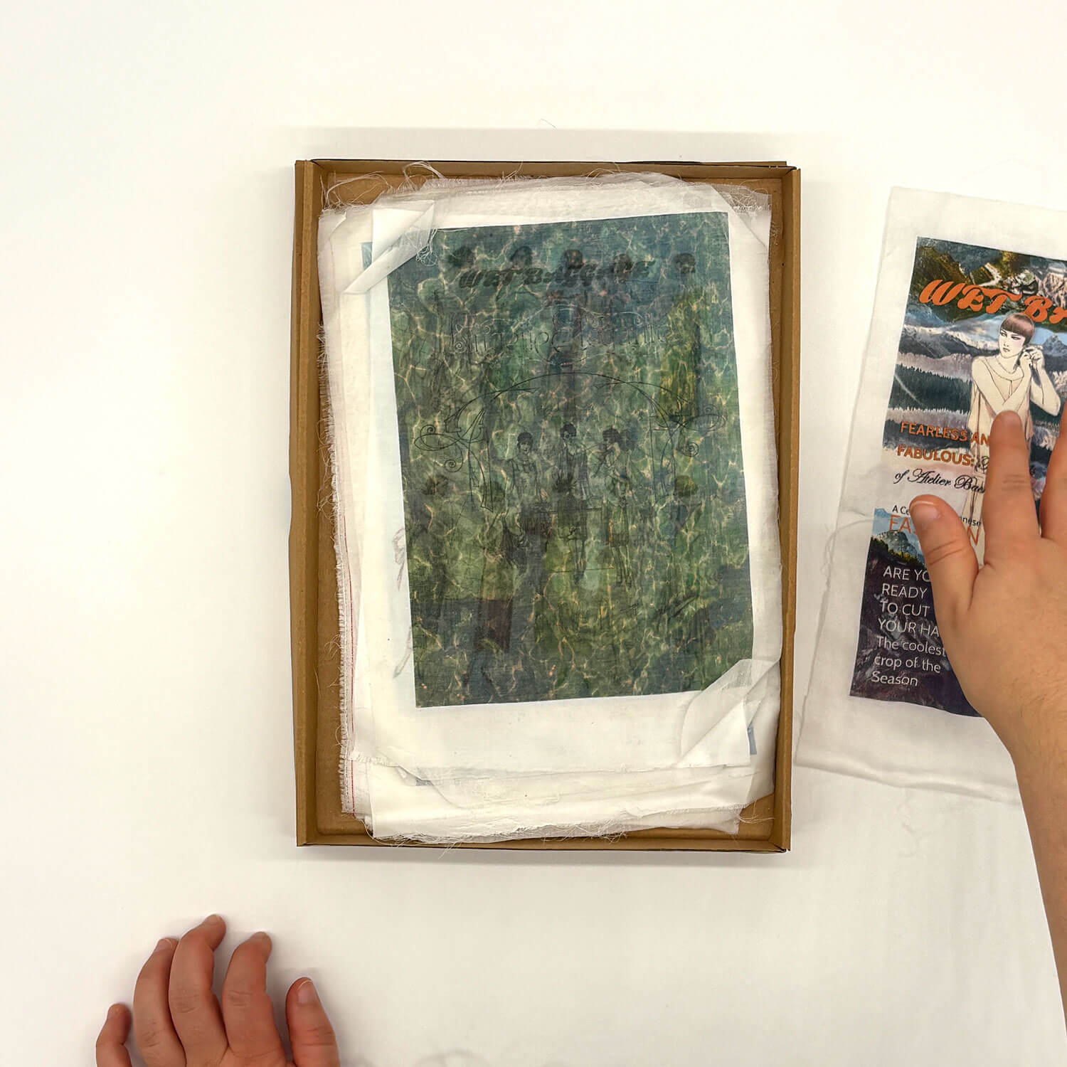 A studio photo of a designer bag and a publication printed on textile