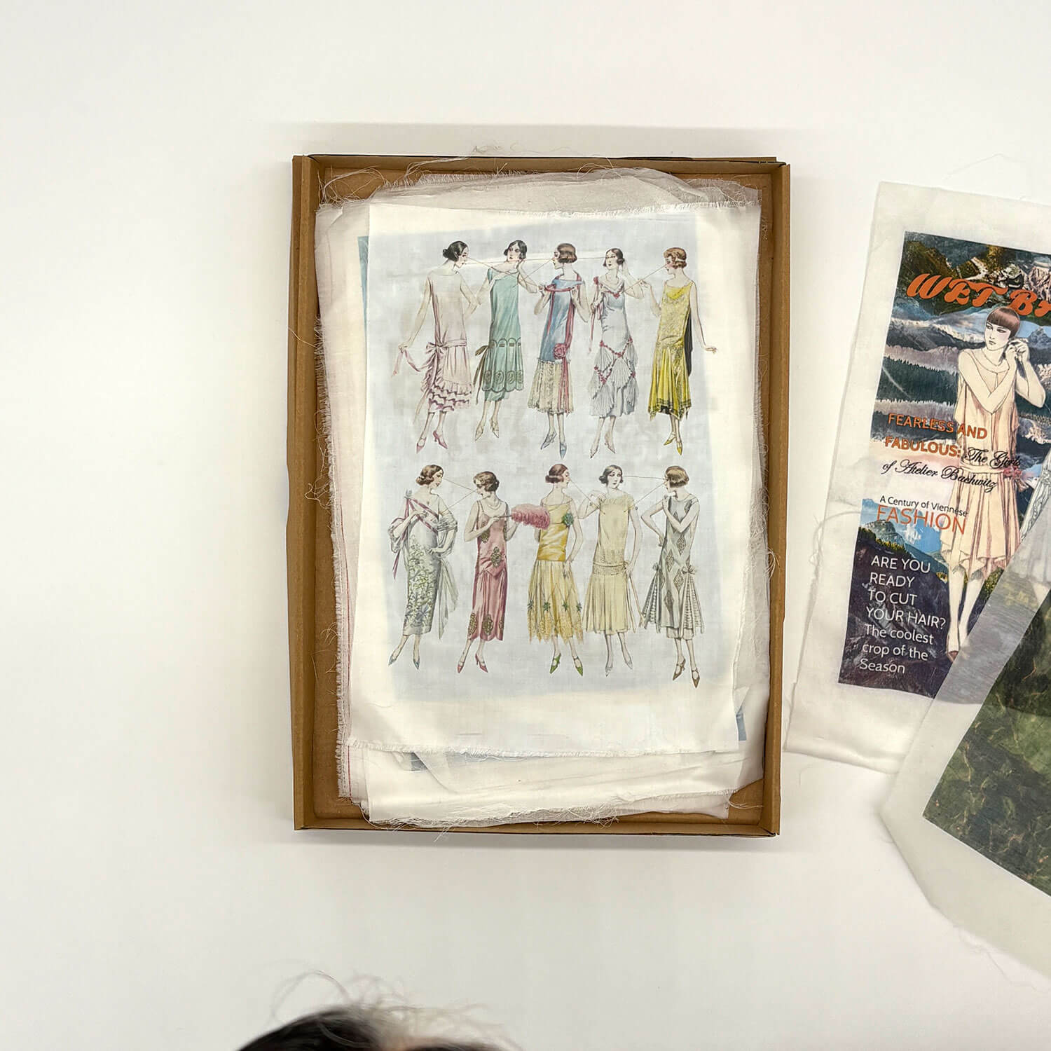 A studio photo of a designer bag and a publication printed on textile