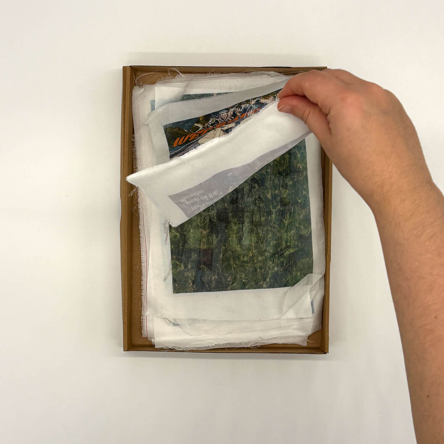 A studio photo of a designer bag and a publication printed on textile