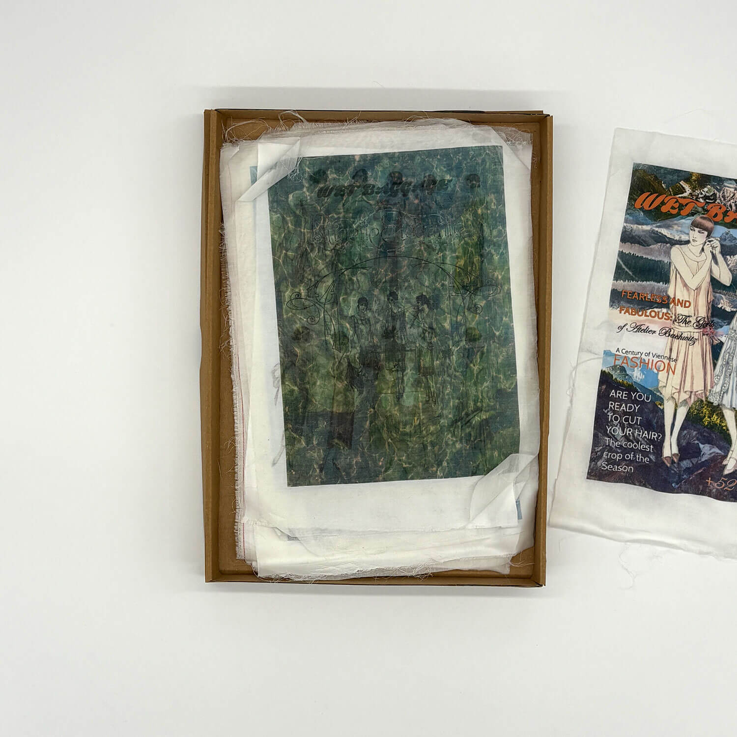 A studio photo of a designer bag and a publication printed on textile