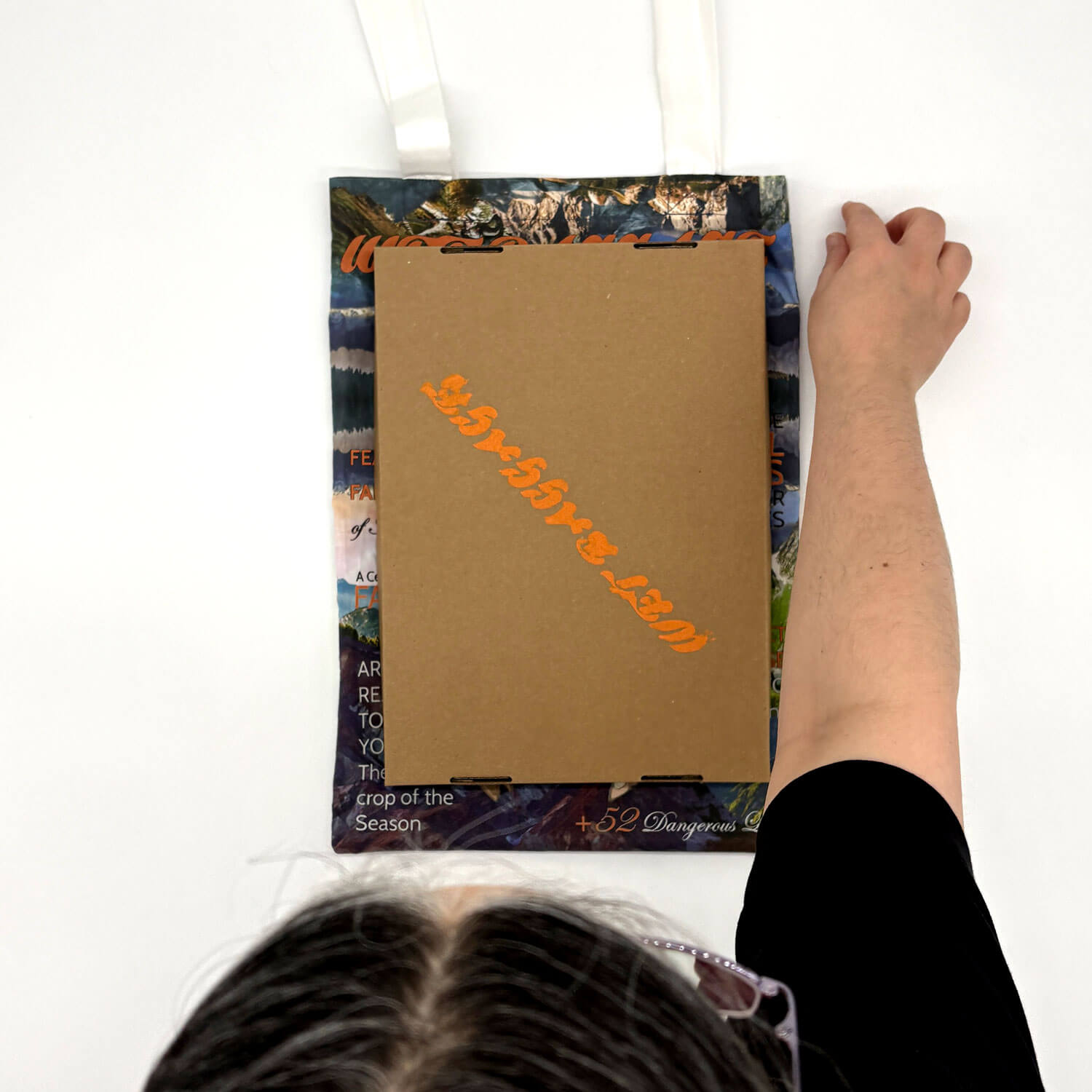 A studio photo of a designer bag and a publication printed on textile