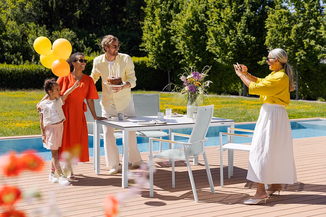 Familie feiert Geburtstag im Garten neben einem Pool, während eine Frau ein Foto macht.