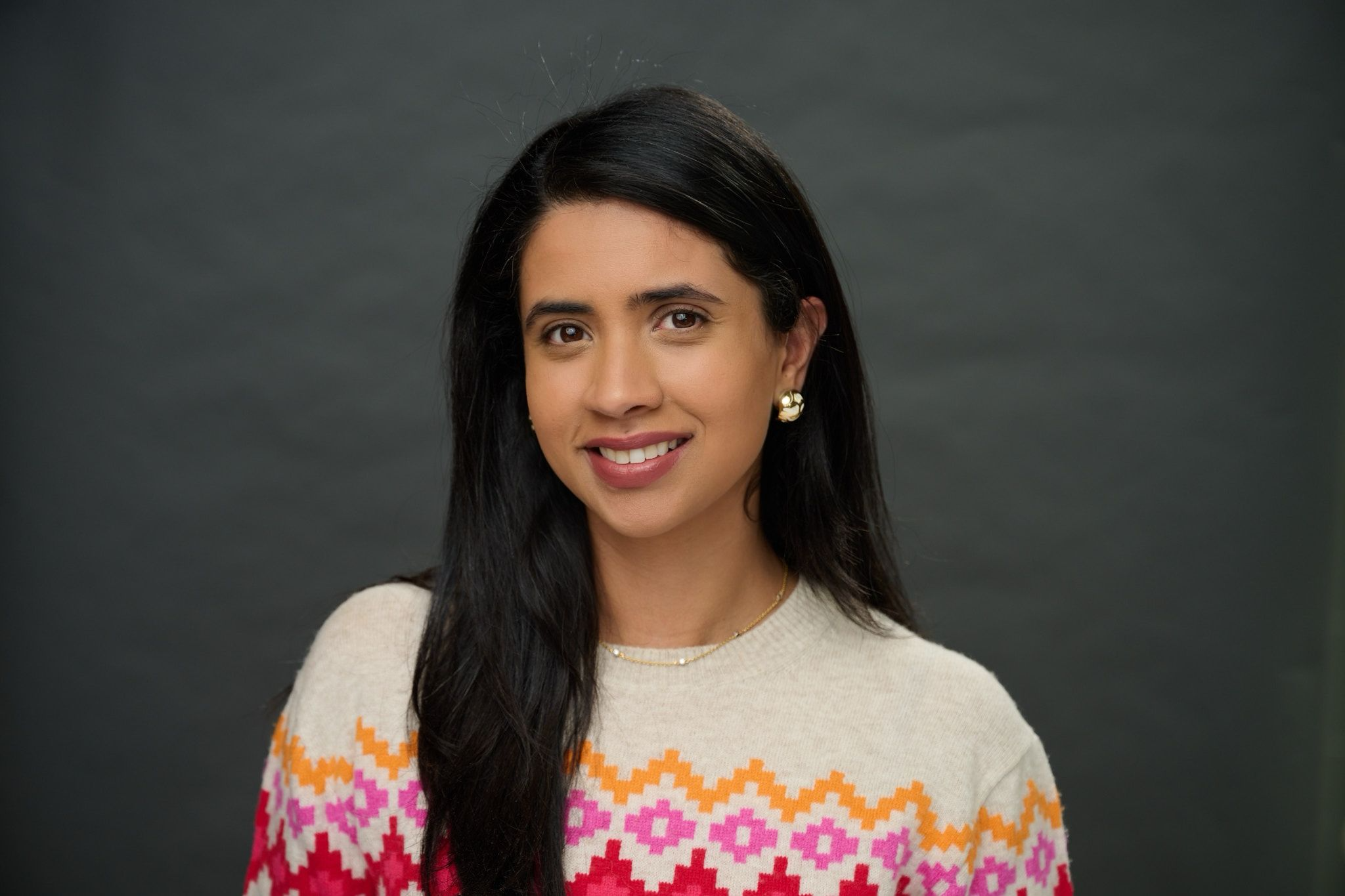 Ana is smiling against a dark gray background