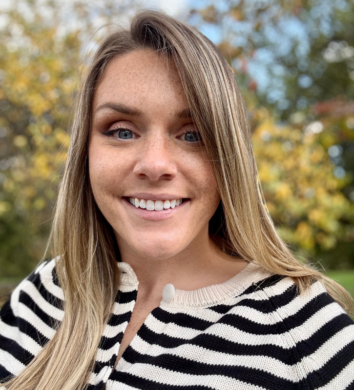 Headshot of Claire Senita, a white woman with long blonde hair and freckles wearing a black and cream striped shirt.