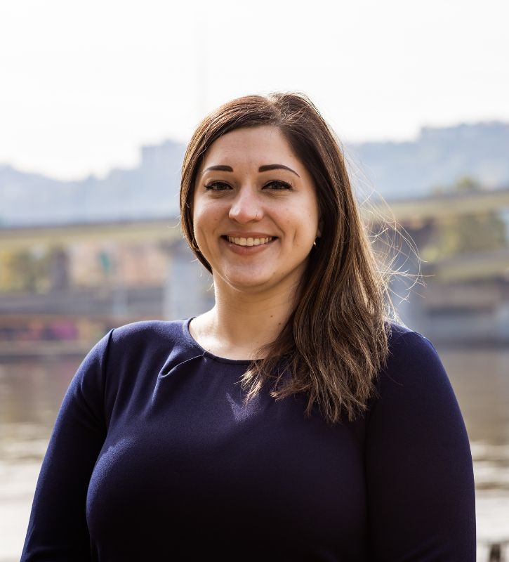 Headshot of Cait Lee, a white woman with shoulder-length brown hair wearing a navy blouse.  