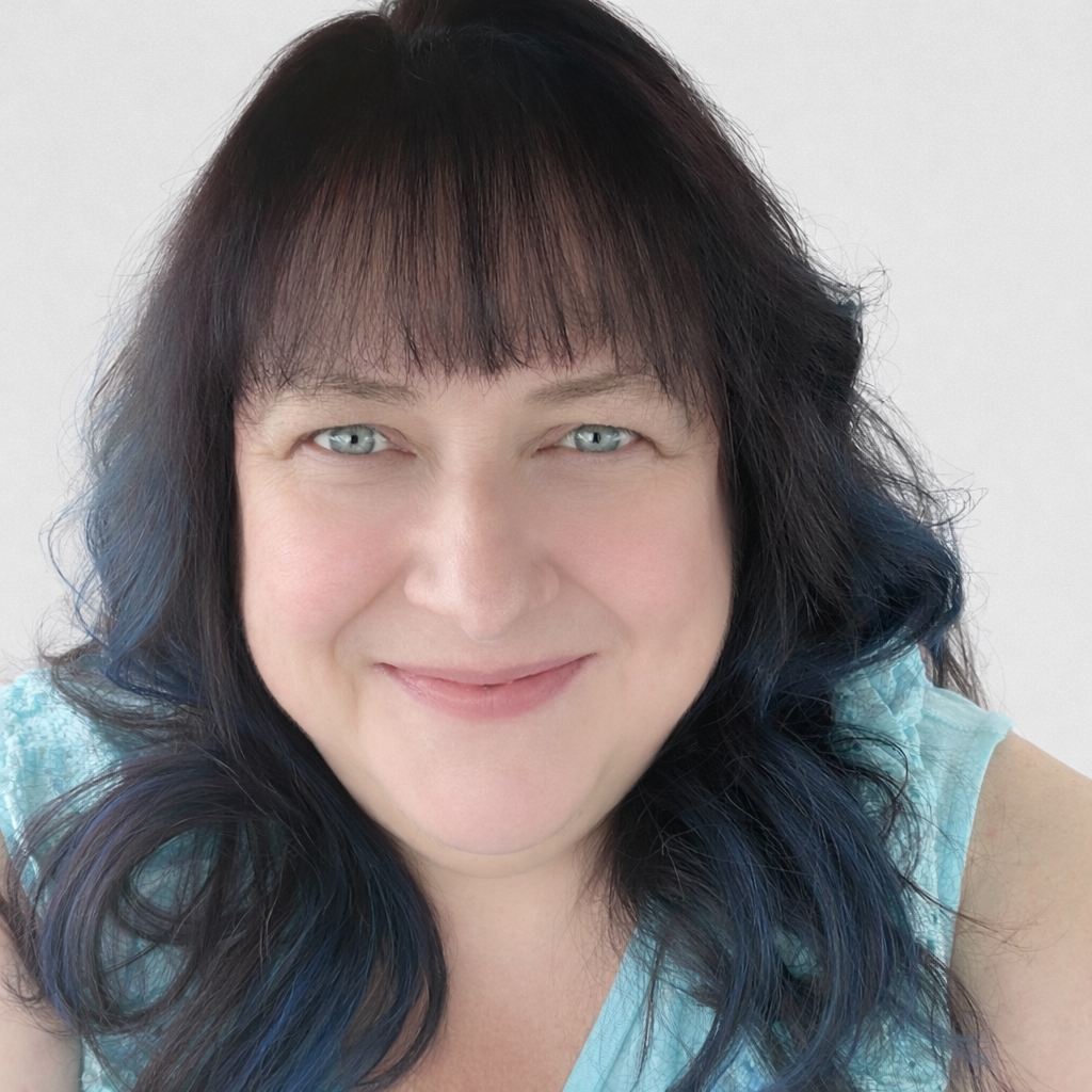 A white woman with chest length brunette hair with bangs. Monica is smiling and is wearing a sleeveless light blue blouse.