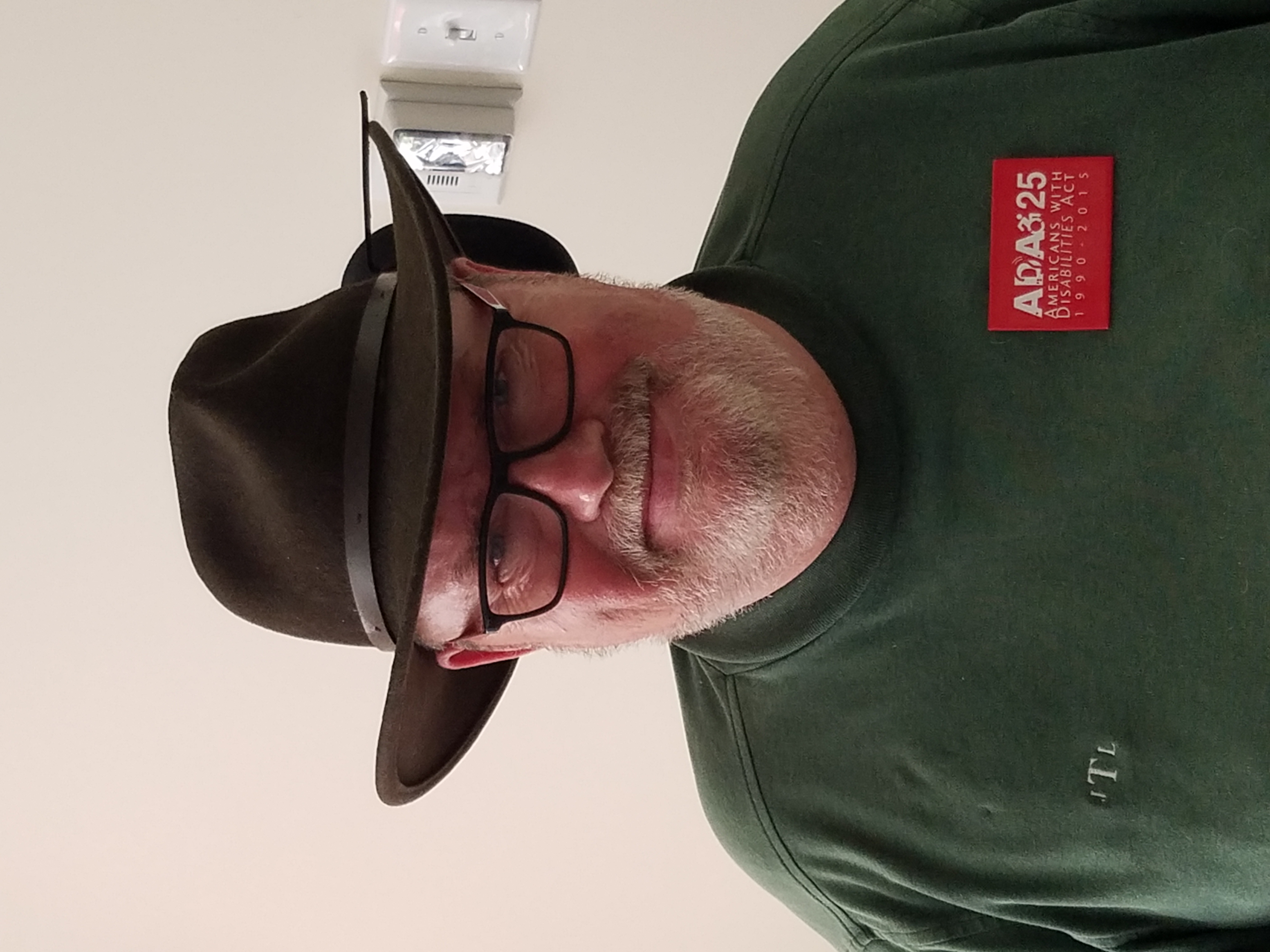 White man with white beard wearing a western style, brimmed hat and glasses.