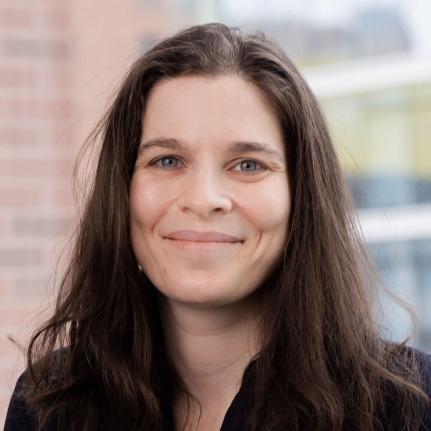 aura , a white person with dark brown hair, wearing a black collared shirt. 