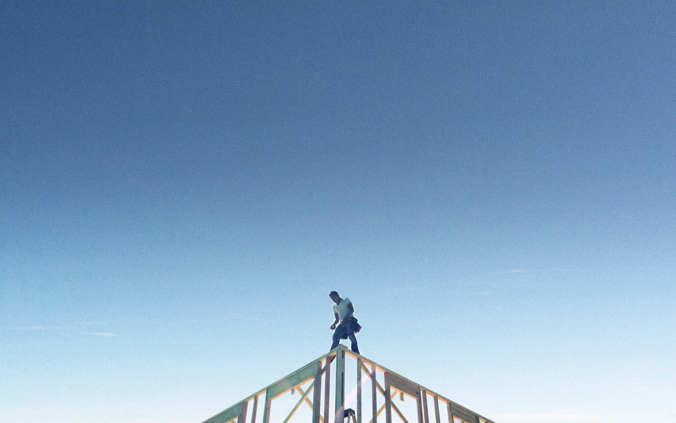 Man standing on top of a house's framework.