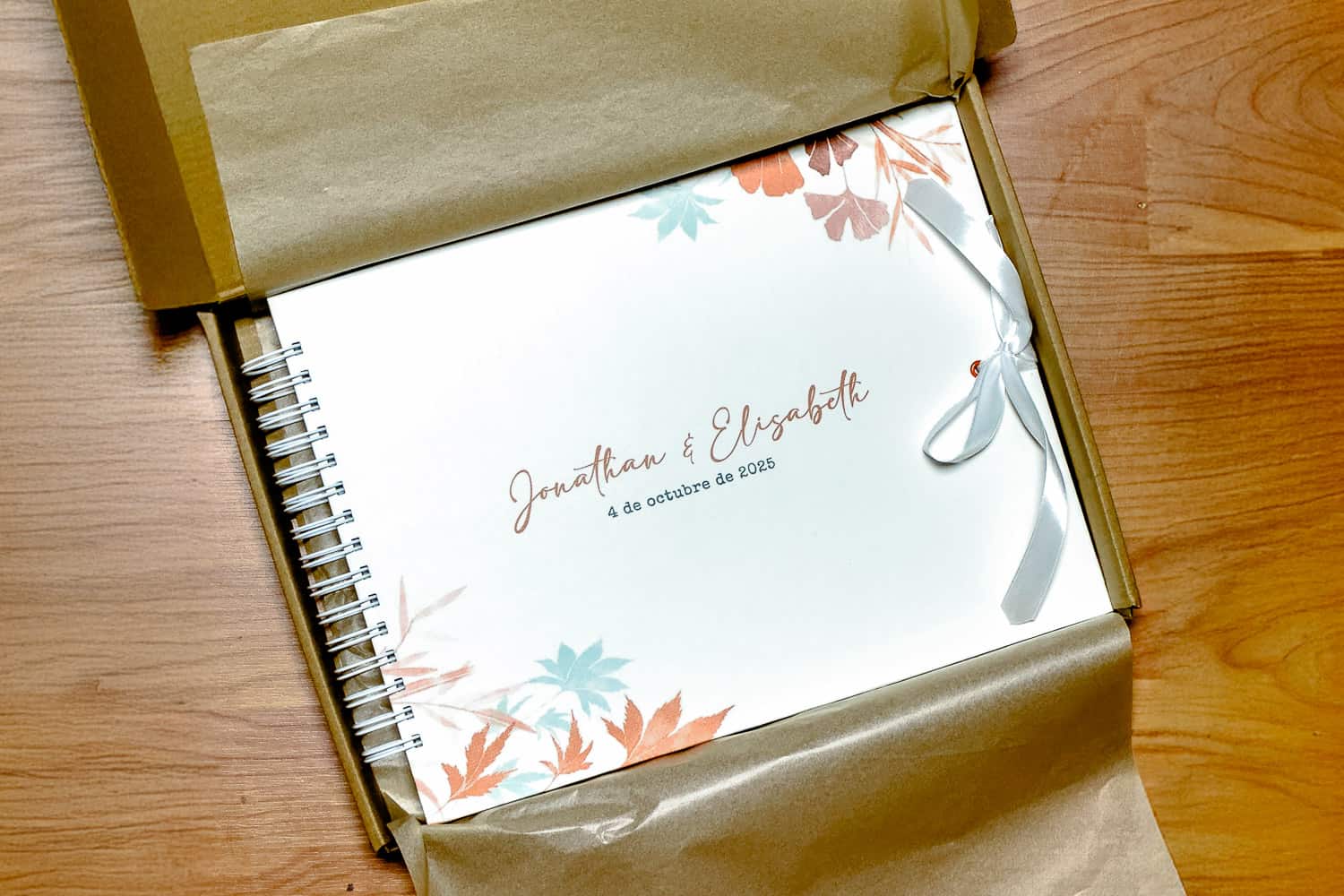 Álbum premium personalizado de Selfriends Fotomatón, con tapa decorada con hojas de colores y los nombres de los novios Jonathan y Elisabeth, presentado en caja de embalaje elegante.