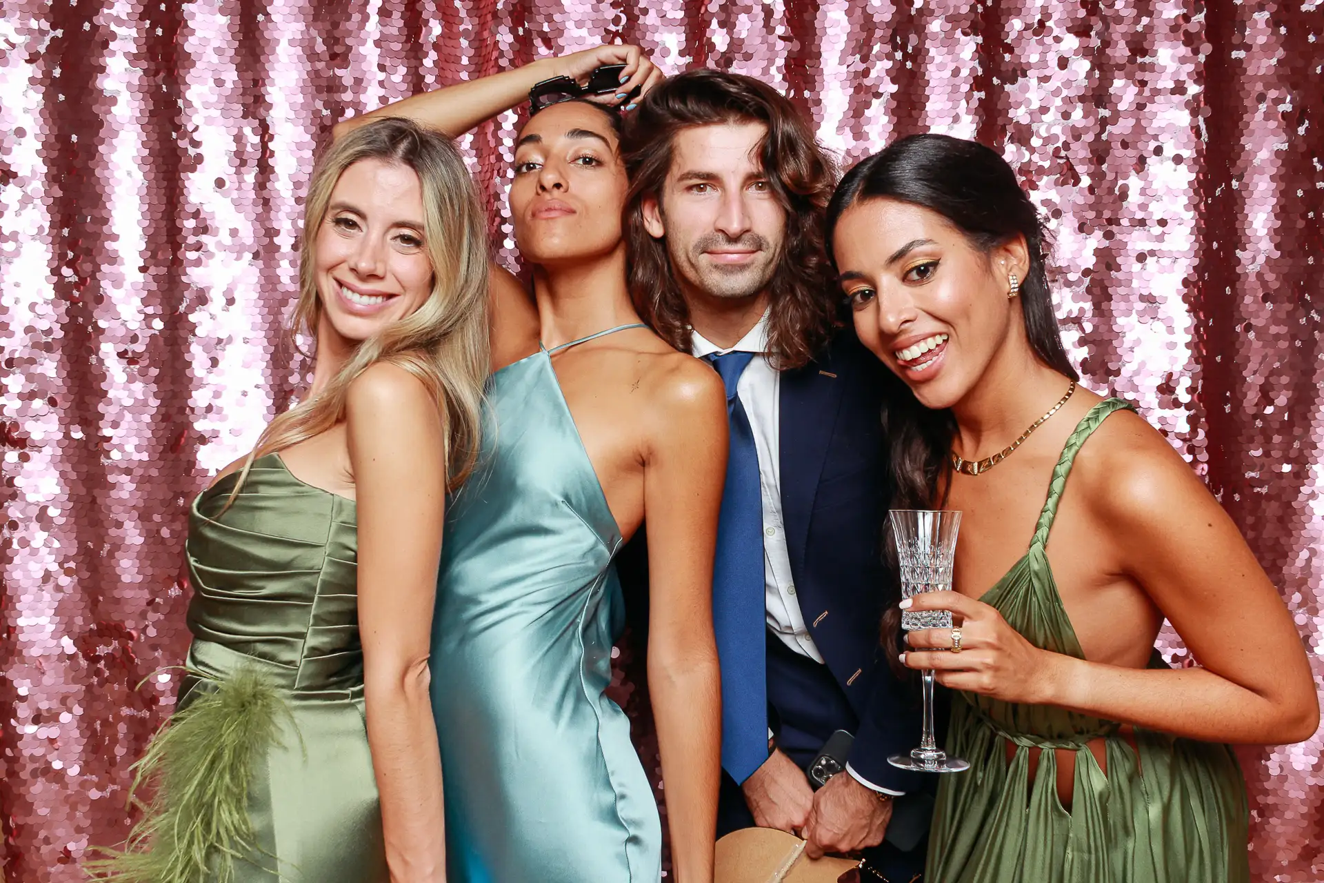Grupo de amigos sonrientes posando elegantemente frente a fondo brillante rosado en un fotomatón de Selfriends durante un evento en Barcelona.