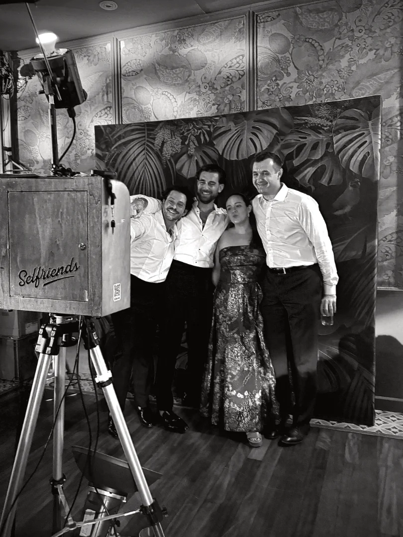 Guests posing beside a Selfriends photo booth at a wedding reception.