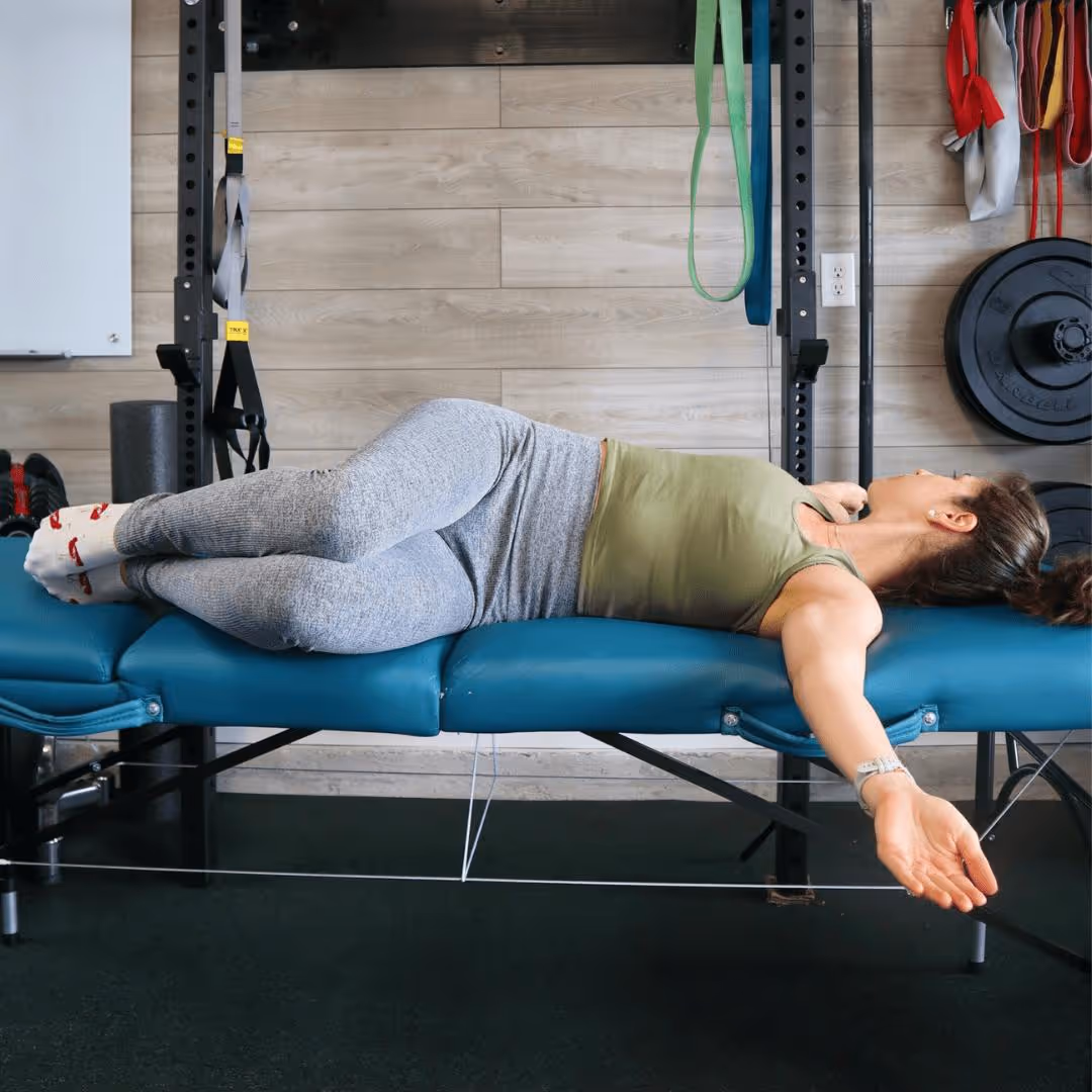 A girl lying on her back with her arms out in a T, rotating her legs all the way to each side