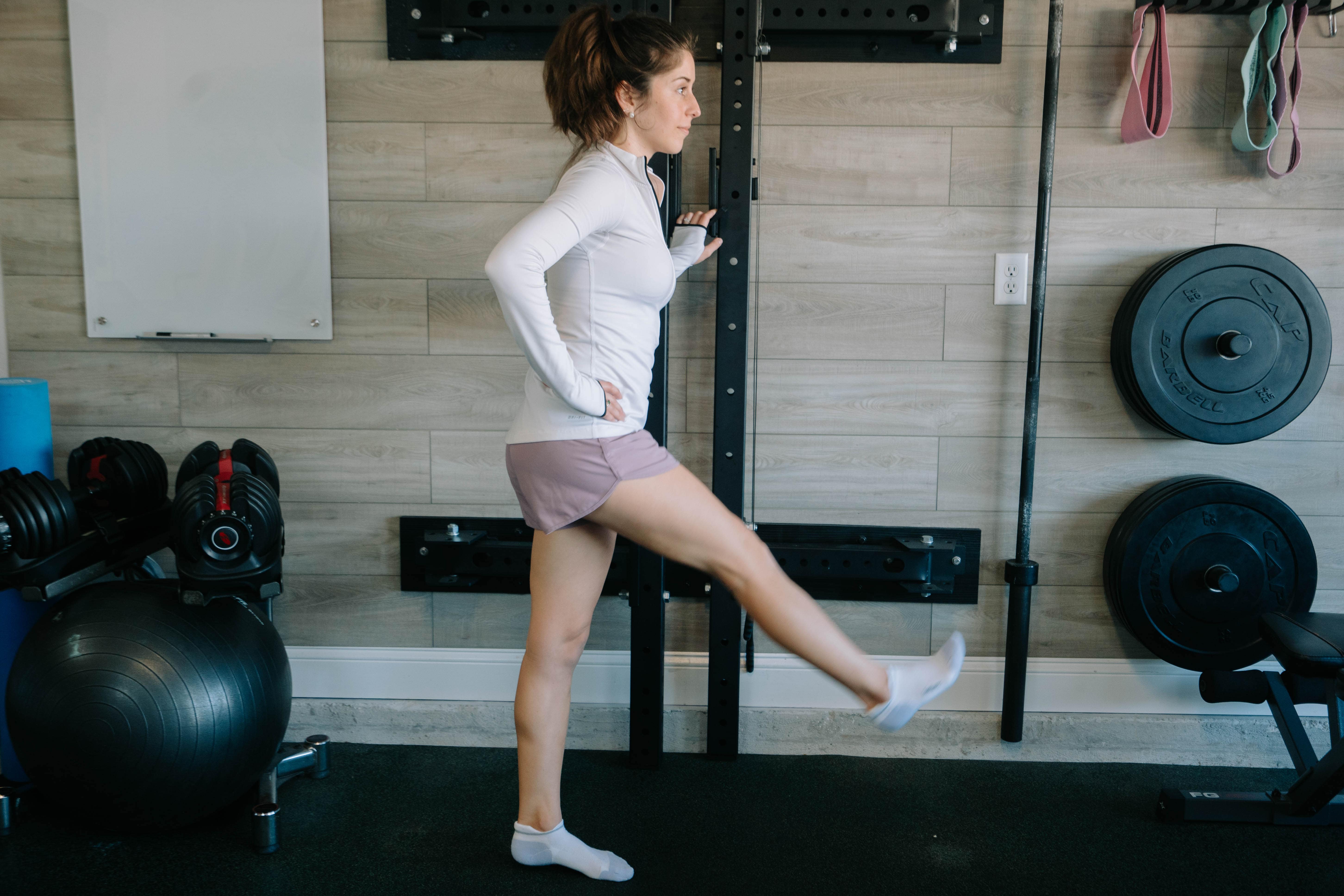 A woman in the starting position for Leg Swings