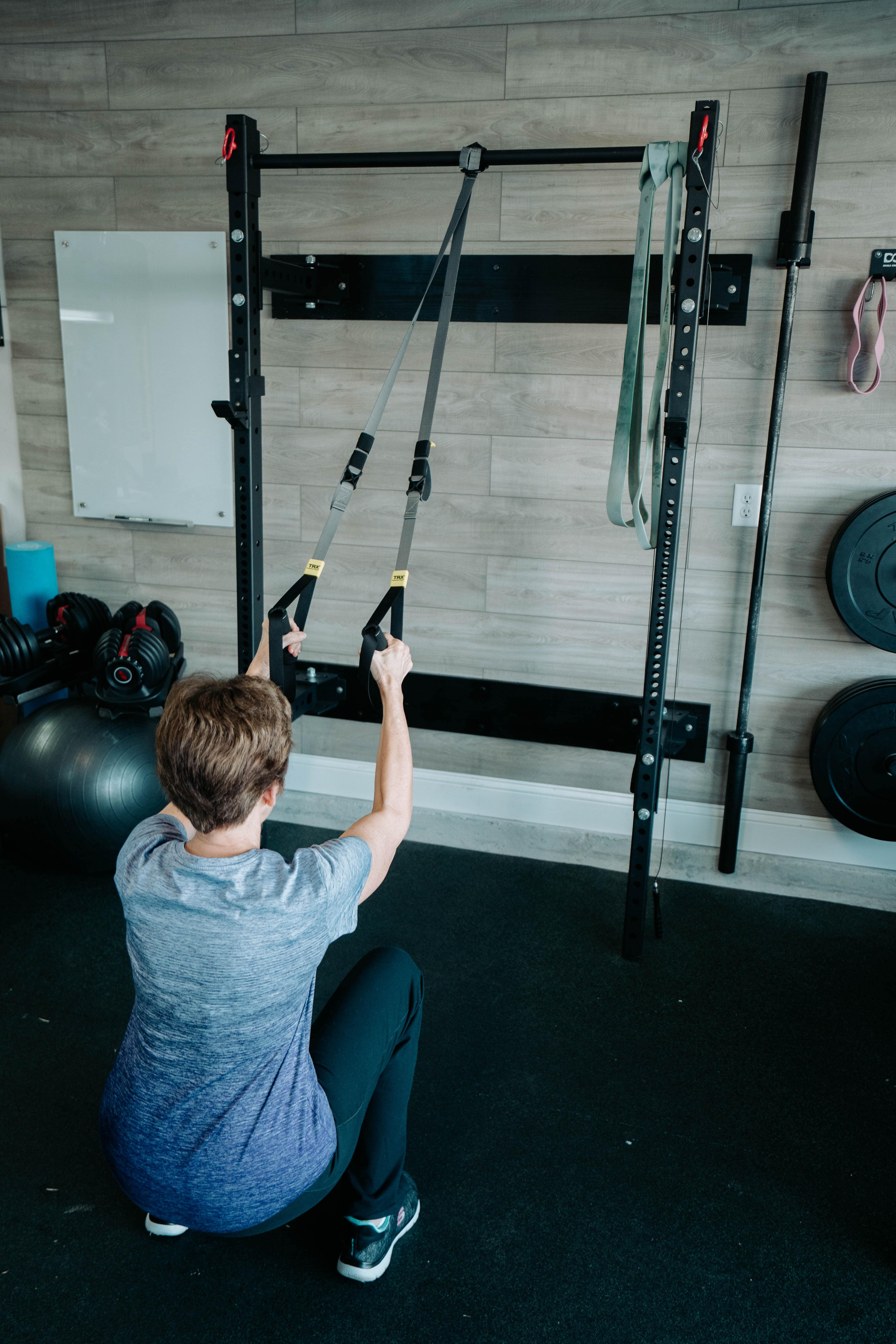 Elderly woman doing suspension Trainer Squats