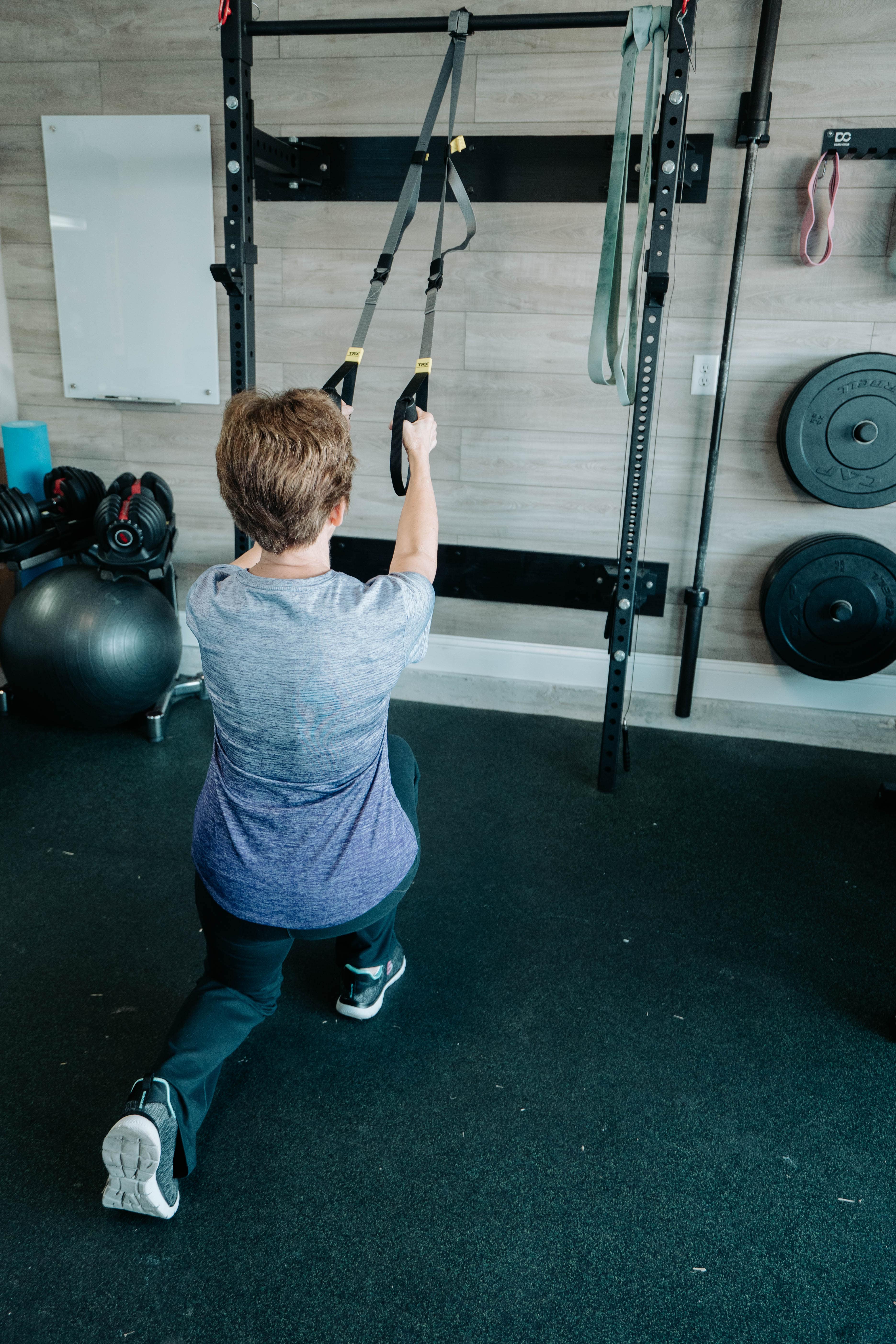 Elderly woman demonstrating suspension trainer back lunges