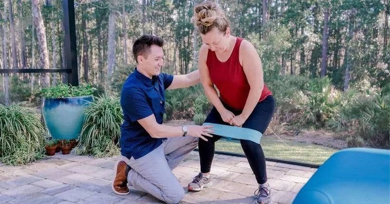 Dr. Michael Derry coaching a patient through resistance-band exercises during an in-home physical therapy session in Jacksonville