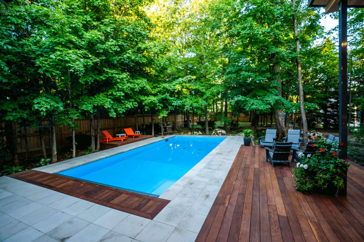 Backyard pool with stone walkway and large trees.