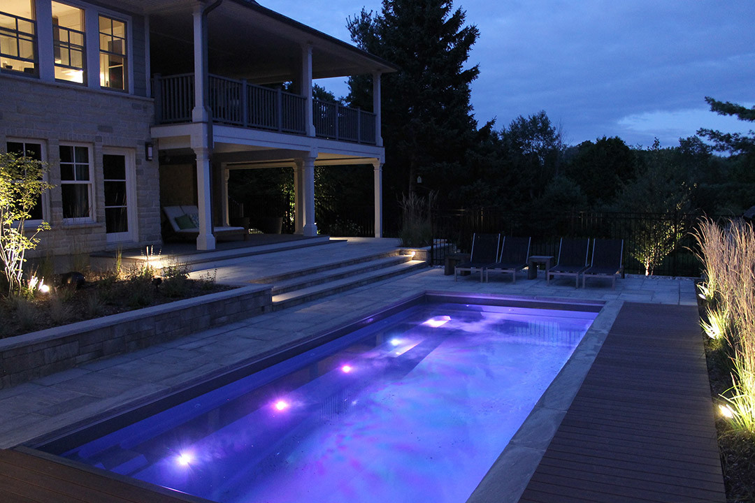 An outdoor pool with pool lights and light landscape.