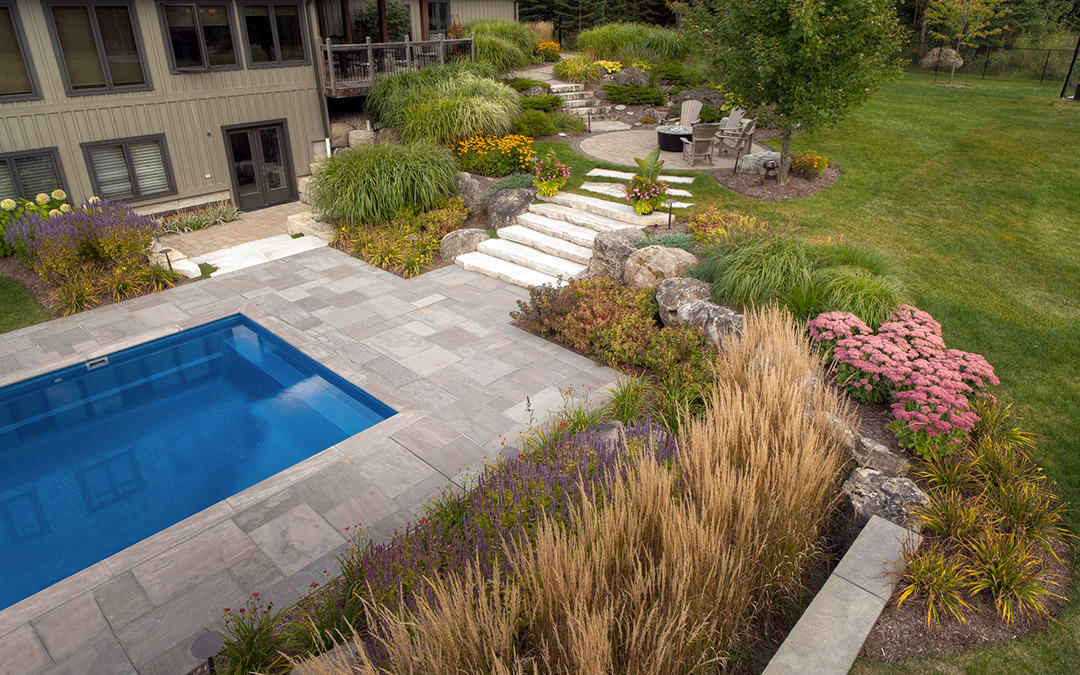 An aerial view of a small outdoor pool with a large garden.