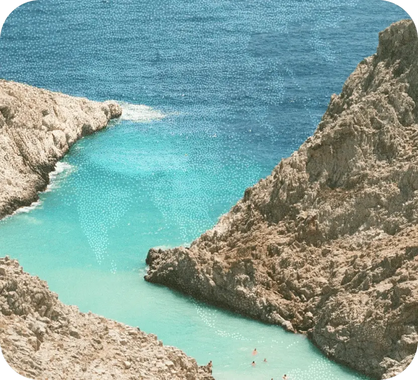 Clear turquoise water cove surrounded by rocky cliffs with people swimming near the shore.