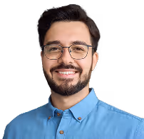  A cheerful man in glasses and a blue shirt, showcasing a warm smile and inviting presence.