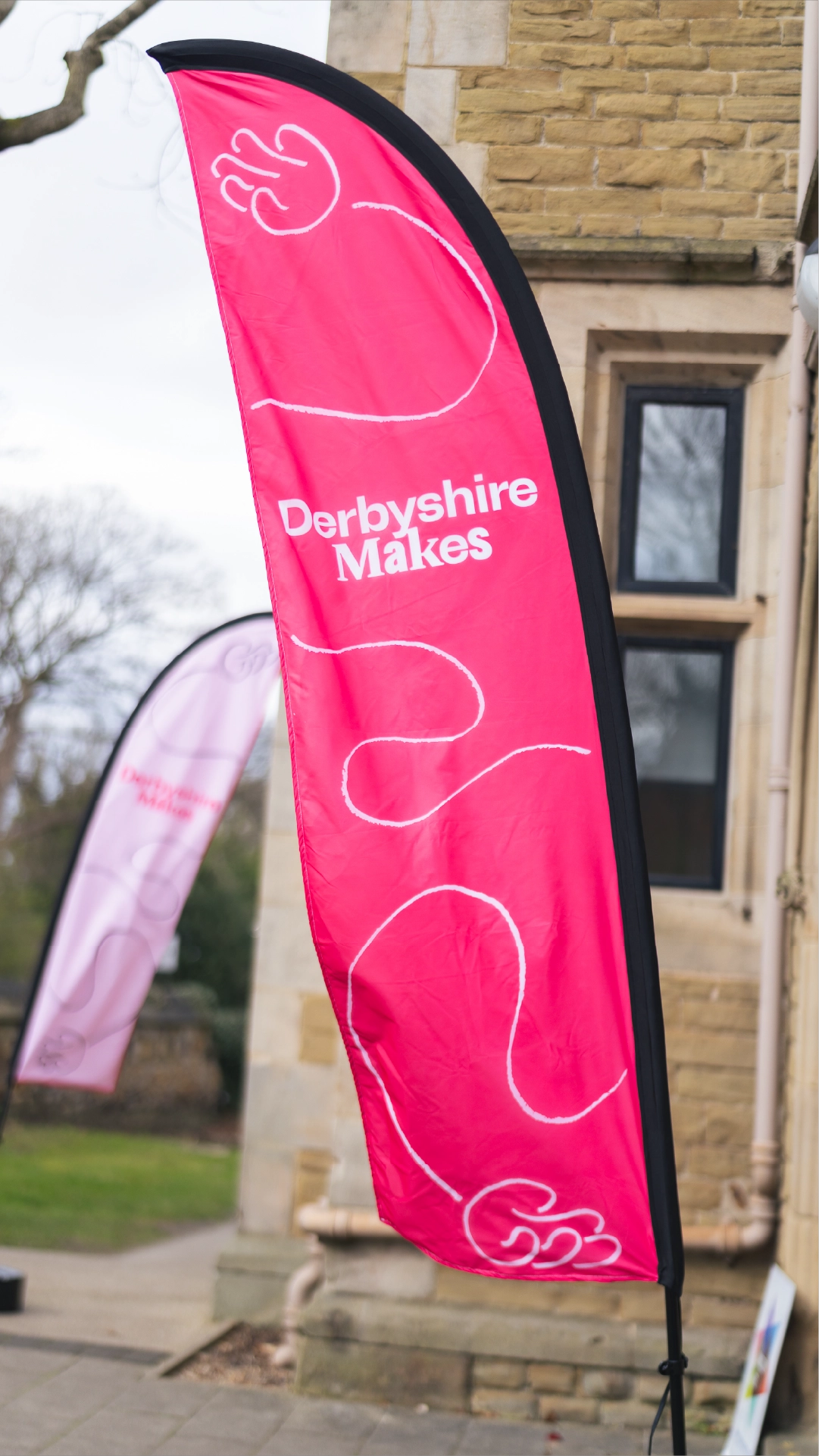 Photo of the flag used at the Derbyshire Makes festival which features the mascot and branding created by Sanna Studio