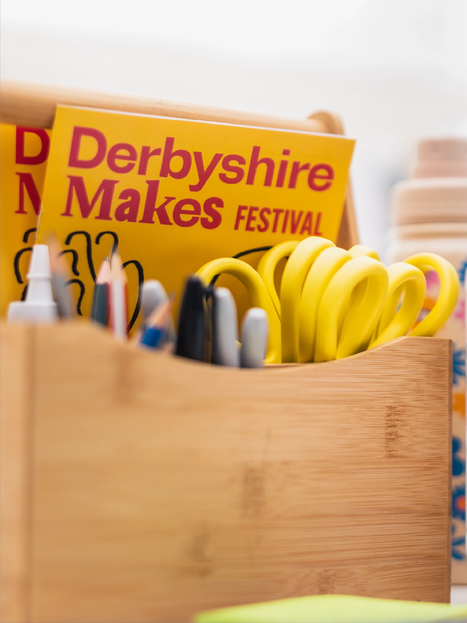 Photograph of the 2025 Derbyshire Makes Festival programme in a stationary holder, featuring the brand identity designed by Sanna Studio