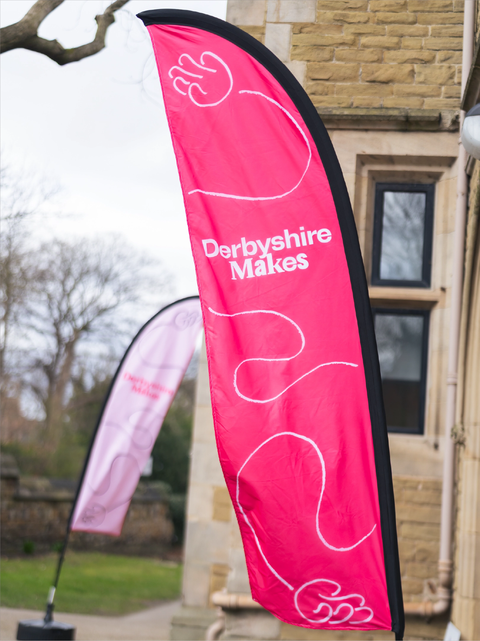 Photo of the flag used at the Derbyshire Makes festival which features the mascot and branding created by Sanna Studio