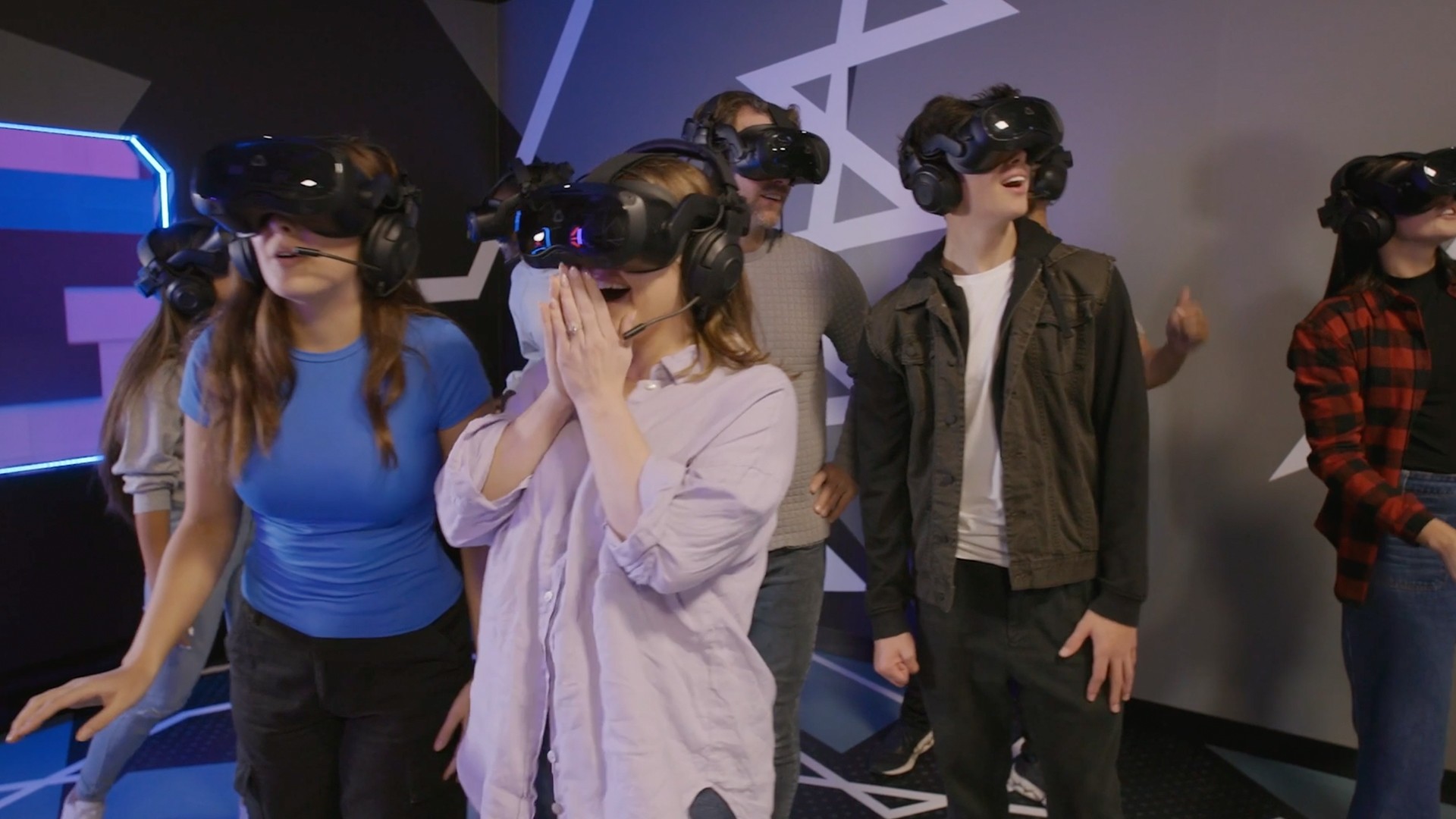A group of friends in VR headsets react with excitement during a Zero Latency game.
