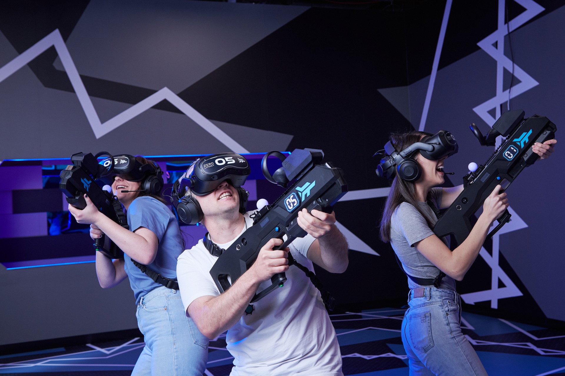 Three players in VR headsets aim their blasters during a Zero Latency game.