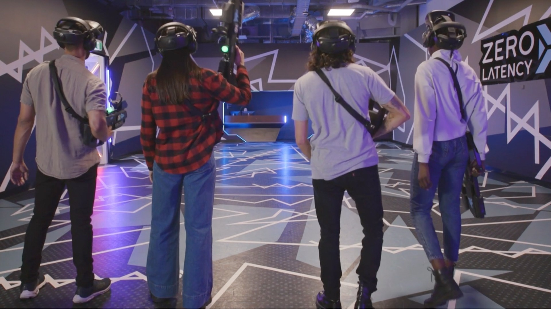 Four players in VR headsets walk into a free-roam VR game space.