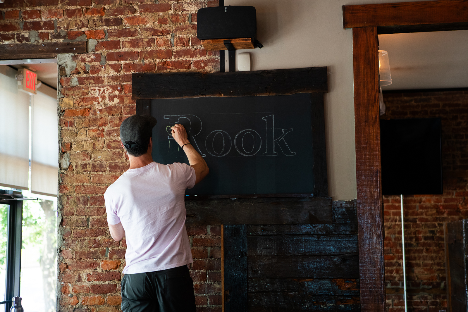 Close-up of an artist illustrating a branded logo on a chalkboard, captured by Camos Media.