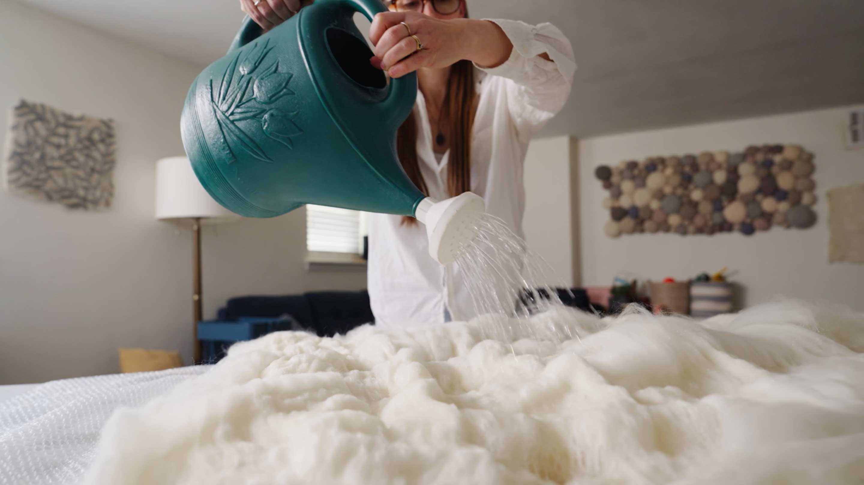 Woman watering wool for a Fibershed sustainable textile project.