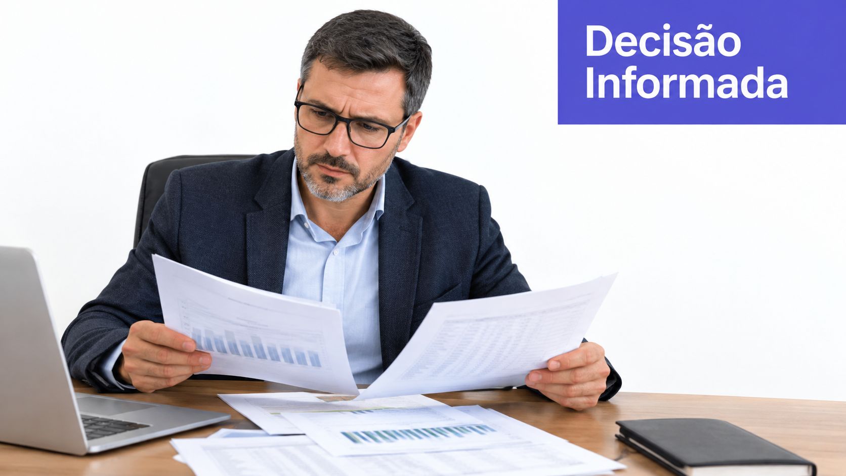 Homem de negócios de óculos analisando gráficos e relatórios financeiros sentado em sua mesa de escritório.