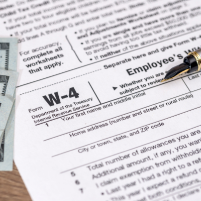 one hundred dollar bills next to a w-4 document